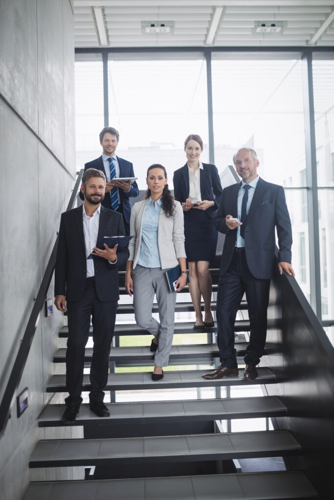 portrait of confident businesspeople standing on staircase in office